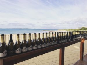 Picturesque view looking out over a beach with a row of Woodsoak Wine Zaaahira Sparkling bottles