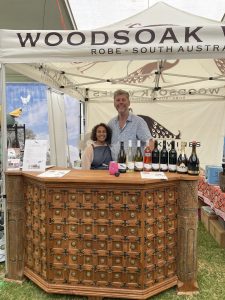 Will and Sonia Legoe stand at an ornate wine bar under a white marquee with Woodsoak Robe South Australia written on it